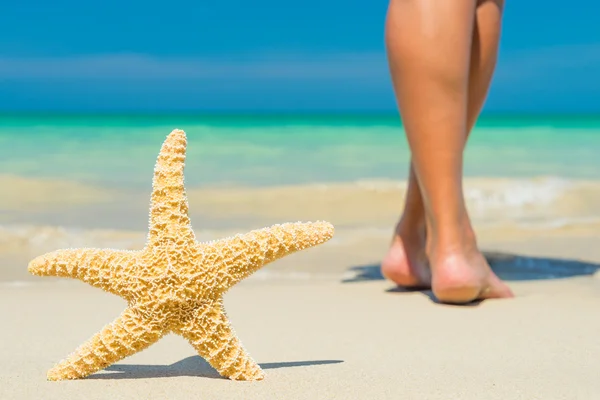 Menschliche Füße auf dem nassen Sand mit einem Seestern. — Stockfoto