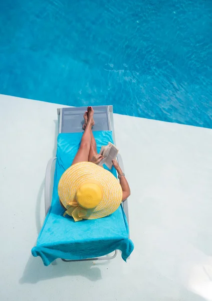 Woman relaxing at the swimming  pool reading a book — Stock Photo, Image