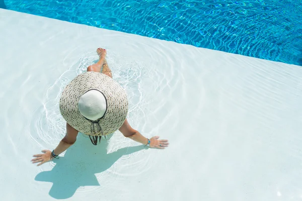 Žena nosí velký klobouk relaxaci u bazénu — Stock fotografie