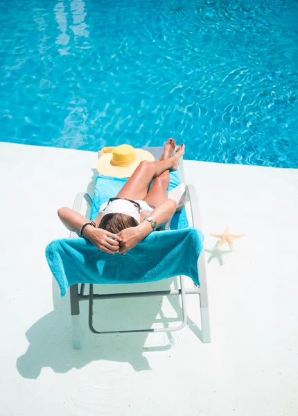 Woman in hat relaxation at swimming pool bed — Stock Photo, Image