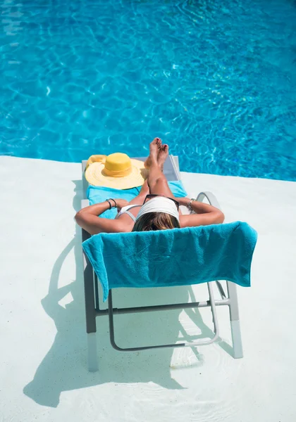 Жінка в капелюсі розслабляється біля басейну ліжка — стокове фото