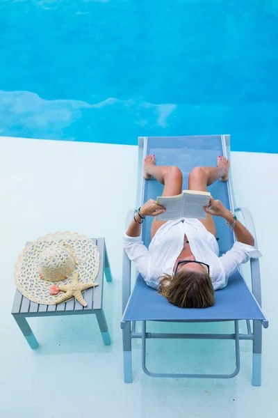 Жінка розслабляється біля басейну читання — стокове фото