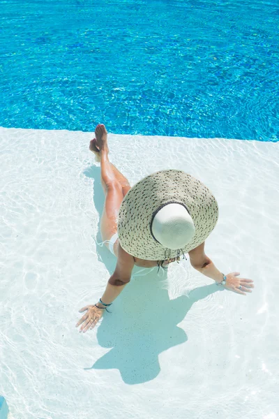 Femme portant un grand chapeau relaxant à la piscine — Photo