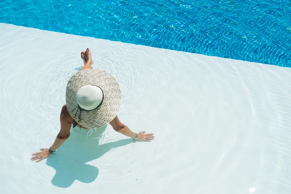 Woman wearing a big hat relaxing at the swimming pool — Stock Photo, Image