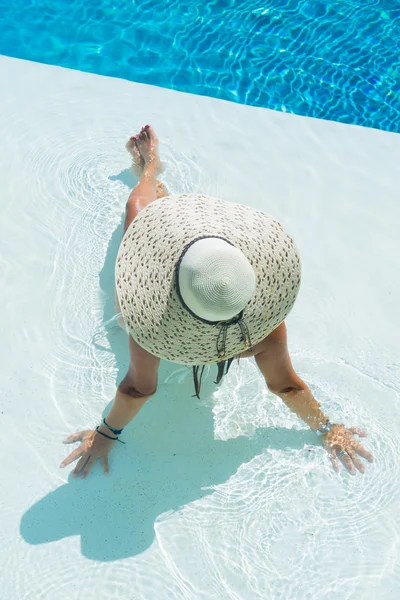 Femme portant un grand chapeau relaxant à la piscine — Photo