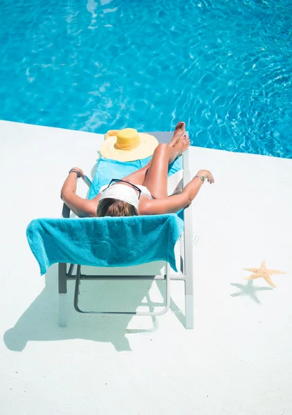 Mujer en sombrero relajación en la cama de la piscina —  Fotos de Stock