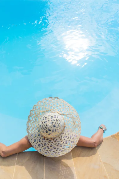 Nierozpoznawalna kobieta w wielkim kapeluszu relaksująca się na basenie — Zdjęcie stockowe
