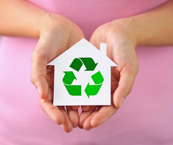 Mãos de mulher segurando casa de papel com símbolo de reciclagem — Fotografia de Stock