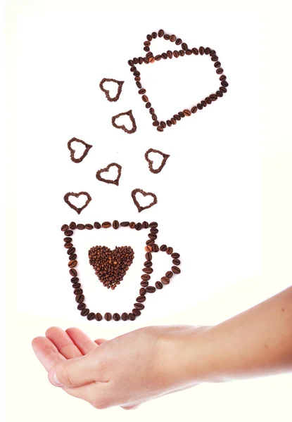 Taza de café de mano llena de granos de café con formas de corazón —  Fotos de Stock