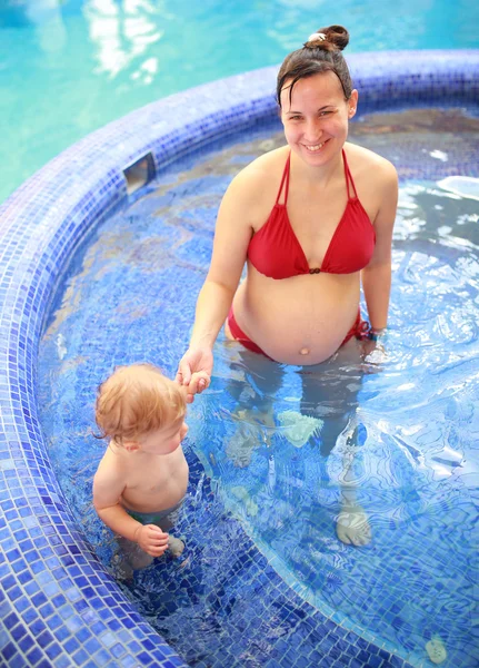 Gravida mamma med sitt härliga barn i poolen — Stockfoto