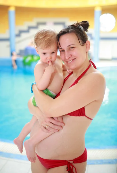 Zwangere moeder met haar mooie kind in zwembad — Stockfoto