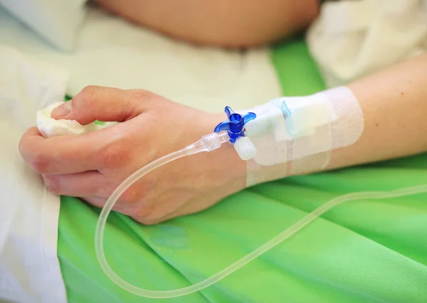 Mano del paciente con infusión en cama de hospital — Foto de Stock