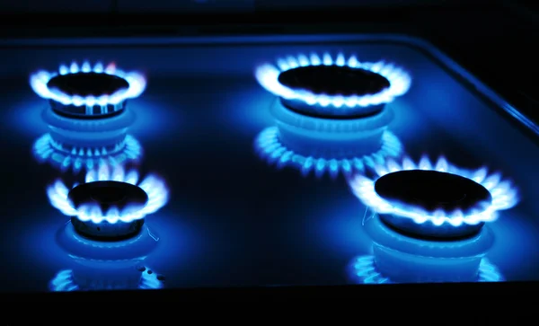 Poêle à gaz bleu dans l'obscurité avec quatre anneaux de flamme — Photo