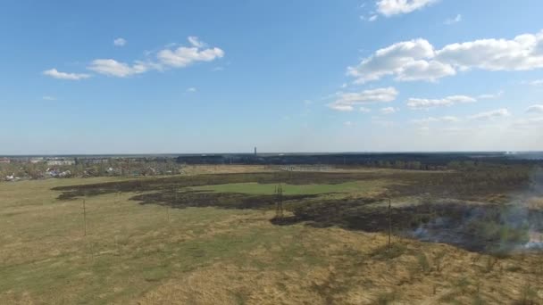 Verbranden van gras in de buurt van dorp — Stockvideo