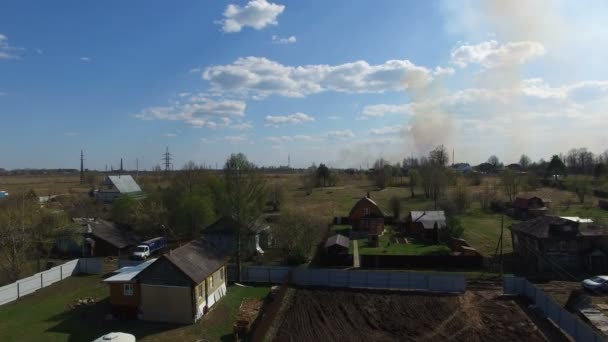 Verbranden van gras in de buurt van dorp — Stockvideo