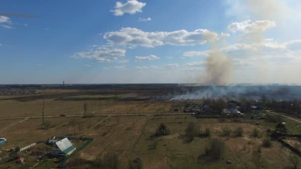 Verbranden van gras in de buurt van dorp — Stockvideo