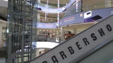 Kashirskaya Plaza alışveriş merkezi, modern iç tasarımı gösteriyor, insanlar asansör ve yürüyen merdiven kullanıyor.