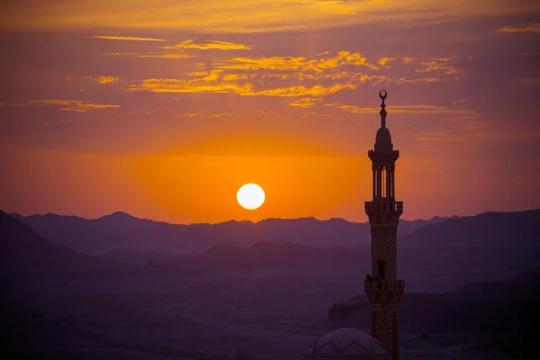 Pôr do sol sobre o deserto com mesquita muçulmana em primeiro plano — Fotografia de Stock