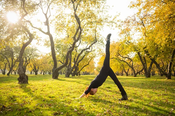 Woman doing yoga in autumn park — Stock Photo, Image