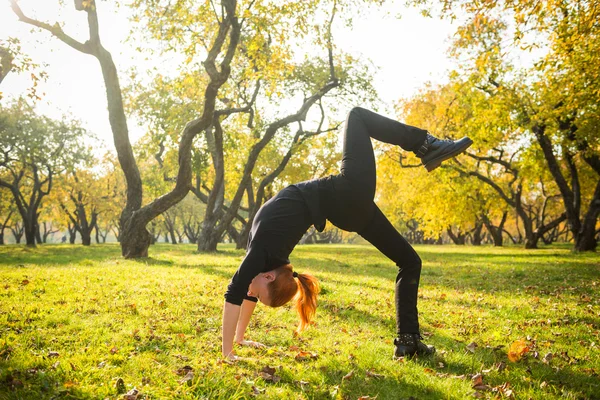 Woman doing yoga in autumn park — Stock Photo, Image