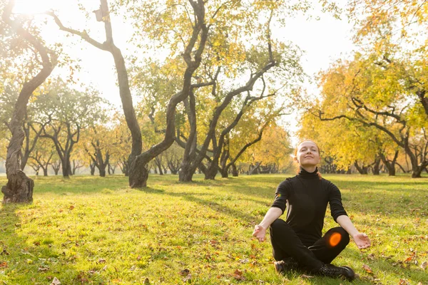 Woman doing yoga in autumn park — Stock Photo, Image