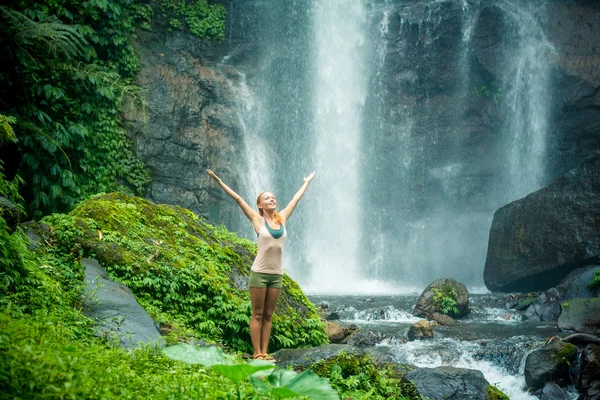 Giovane donna che pratica yoga vicino alla cascata — Foto Stock