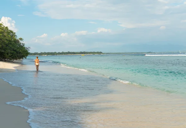 Young woman walking along tropical beach — Stock Photo, Image