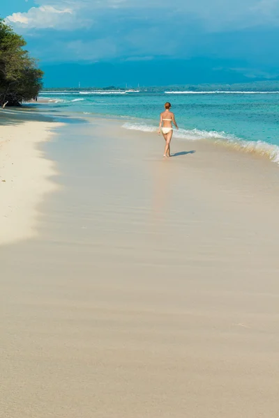 Молодая женщина, идущая вдоль тропического пляжа — стоковое фото