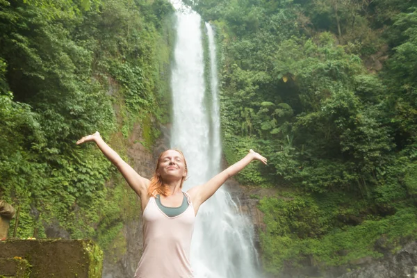 Mladá žena cvičí jógu u vodopádu — Stock fotografie