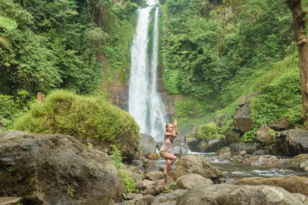 Mladá žena cvičí jógu u vodopádu — Stock fotografie