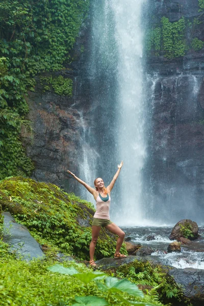 Young woman practicing yoga by the waterfall Royalty Free Stock Images