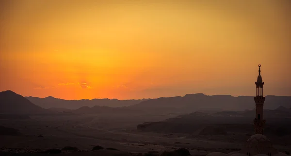 Puesta de sol sobre el desierto con mezquita musulmana en primer plano —  Fotos de Stock