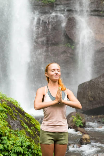 Jeune femme pratiquant le yoga près de la cascade — Photo