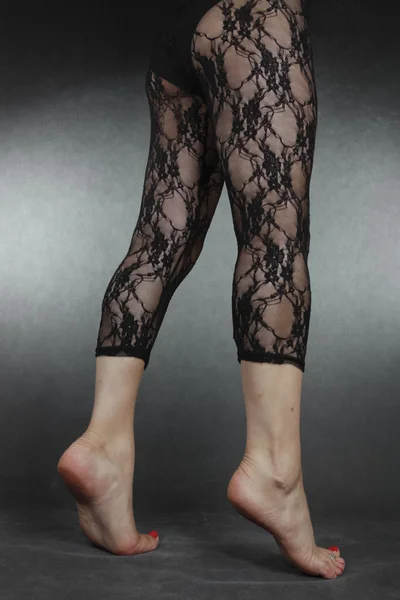 Woman legs wearing black lace leggins over grey background — Stock Photo, Image