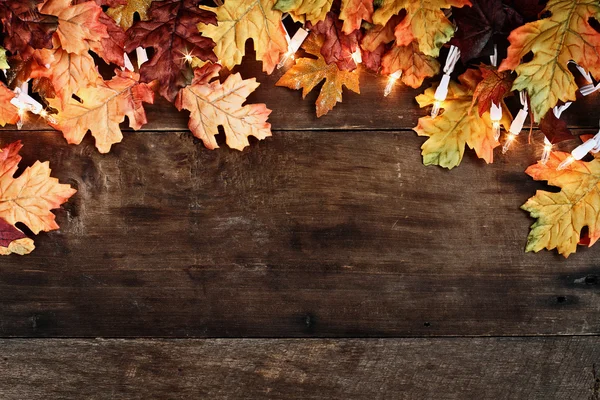 Hojas de otoño y luces sobre fondo de madera — Foto de Stock