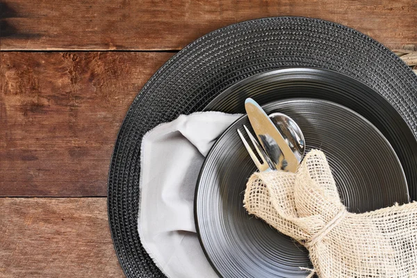 Place Setting of Black Dinnerware over Wooden Background — Stock Photo, Image