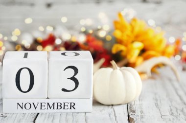 Seçim günü. Tahta bir masanın üzerinde tarihi 3 Kasım ve sonbahar süslemeleri olan beyaz tahta takvim blokları. Bulanık arkaplan ile seçmeli odak. 
