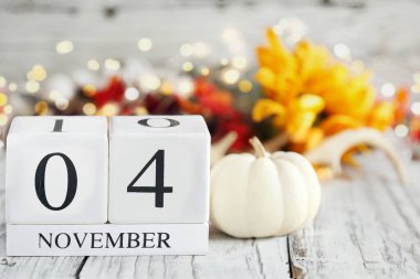 Tahta bir masanın üzerinde tarihi 4 Kasım ve sonbahar süslemeleri olan beyaz tahta takvim blokları. Bulanık arkaplan ile seçmeli odak. 