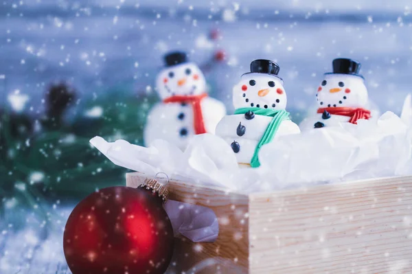 三个冰镇圣诞雪人纸杯蛋糕与胡萝卜鼻子 桑塔帽子和围巾在一个盒子里 具有模糊前景和背景的选择性重点 — 图库照片
