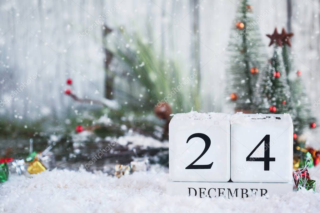 Christmas Eve. White wood calendar blocks with the date December 24th and Christmas decorations with snow. Selective focus with blurred background. 