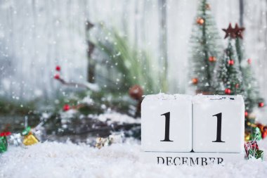 11 Aralık tarihli beyaz tahta takvim blokları ve karlı Noel süslemeleri. Bulanık arkaplan ile seçmeli odak. 