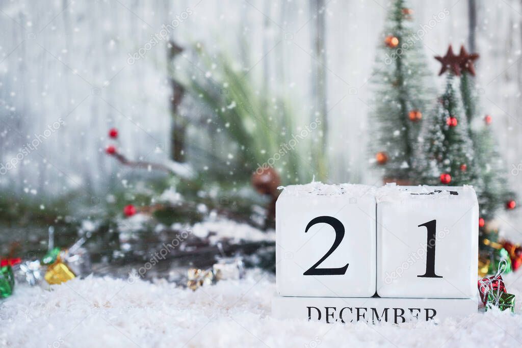 Winter Solstice. White wood calendar blocks with the date December 21st and Christmas decorations with snow. Selective focus with blurred background. 