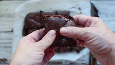 Yapışkan taze çikolatalı browni 'yi tutan ve parçalayan bir kadının elleri..