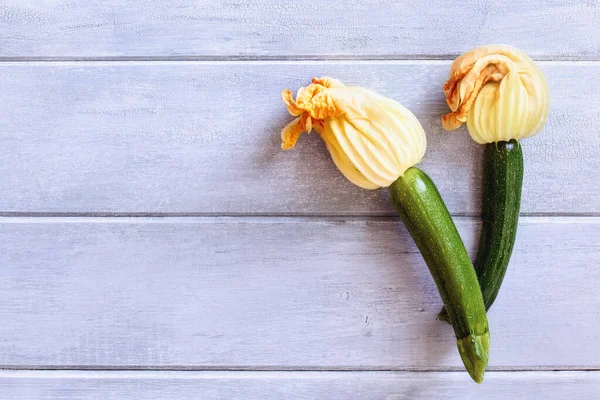 素朴な青い木のテーブルの上に花が付いている赤ん坊Courgetteまたはズッキーニのスカッシュのフラットレイ コピースペースで上から撮影 — ストック写真