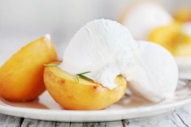 Kahverengi şeker ve taze biberiye filizlerinde pişirilmiş taze ev yapımı kavrulmuş şeftali ve vanilyalı dondurmayla servis edilir. Bulanık arkaplan ile seçmeli odak. 