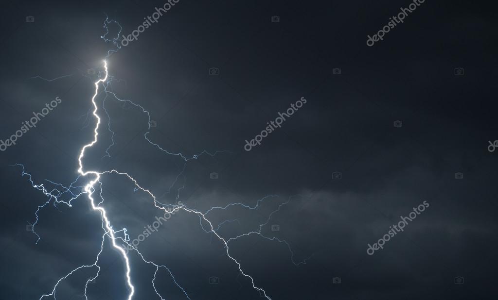 Fork lightning striking down during summer storm Stock Photo by