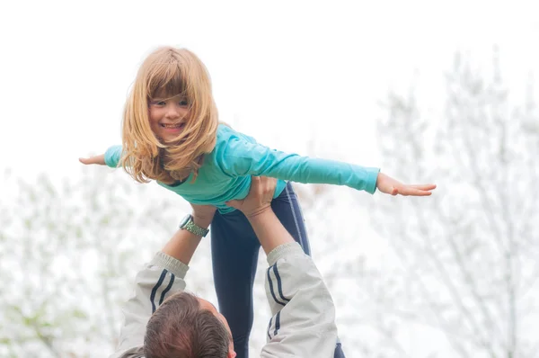 Little girl lifted high in the air by her father — Stock Photo, Image