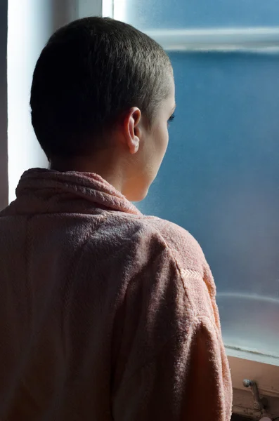 Young cancer patient standing in front of hospital window — Stock Photo, Image