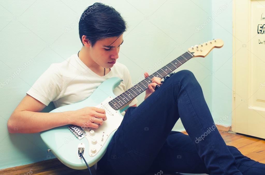 Chico guapo adolescente tocando la guitarra el ctrica en 