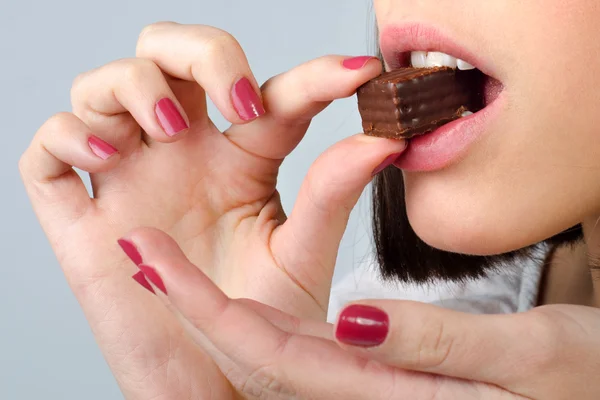 회색 backgro에 고립 된 초콜릿 쿠키를 먹는 여자의 세부 사항 — 스톡 사진